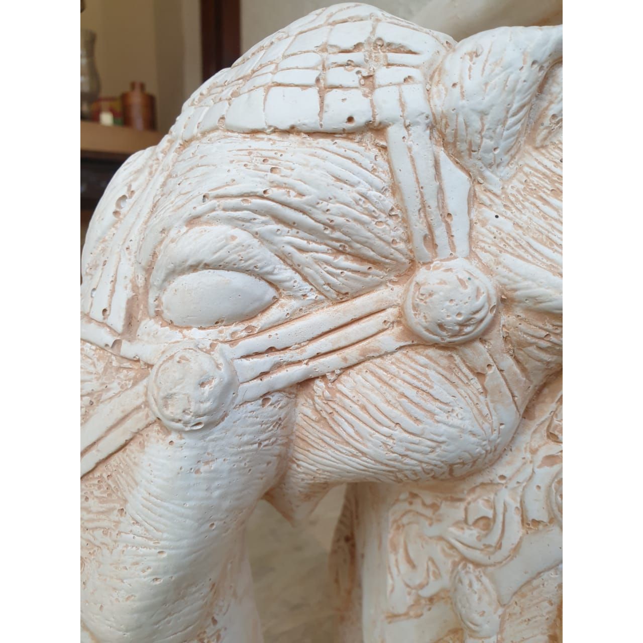 A close-up of a carved wooden pedestal with three elephant figures serving as legs, showcasing intricate details on their bodies and heads