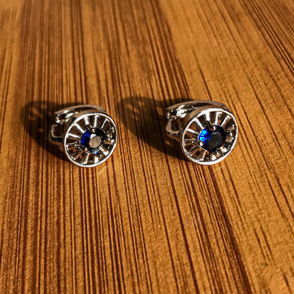 Two silver-colored stud earrings shaped like arc reactors, each with a blue crystal in the center.