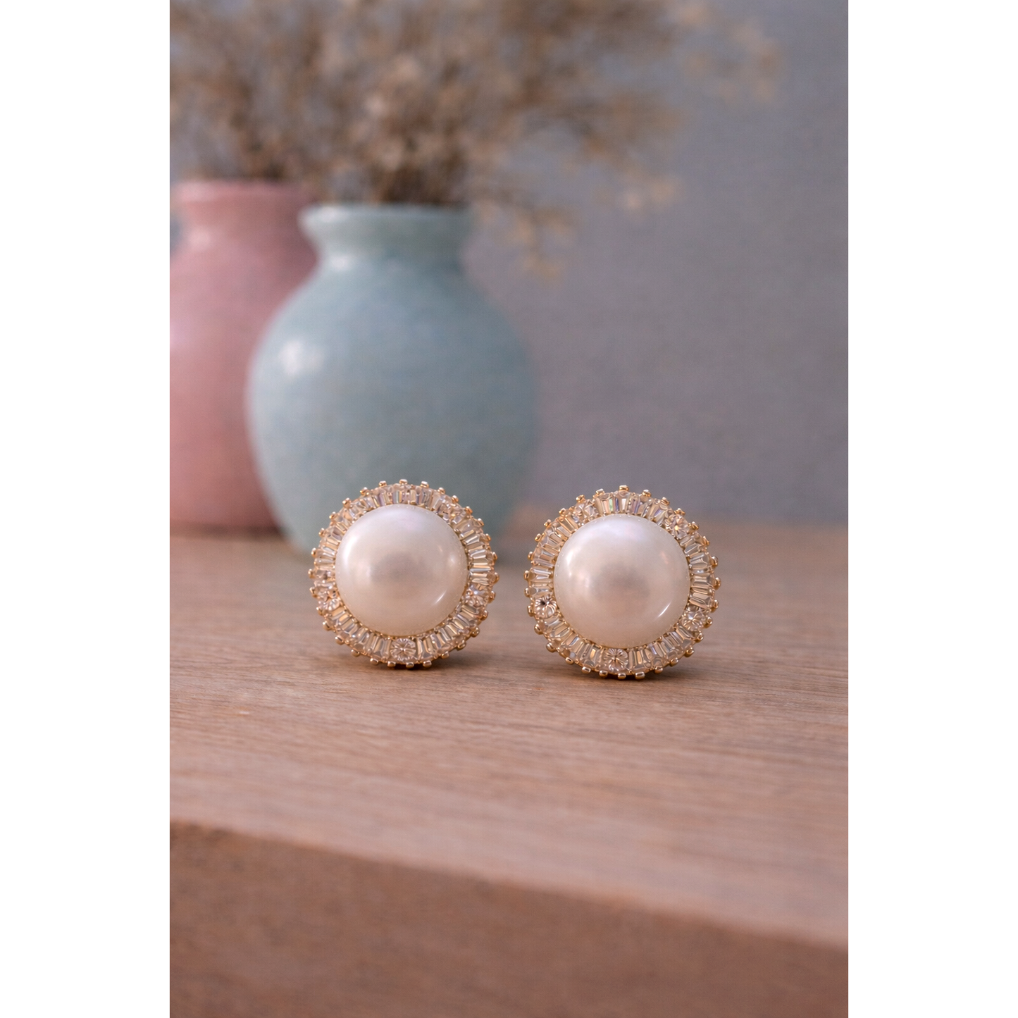 Gold tone pearl halo clip on stud earrings with baguette crystal surround placed on wooden surface