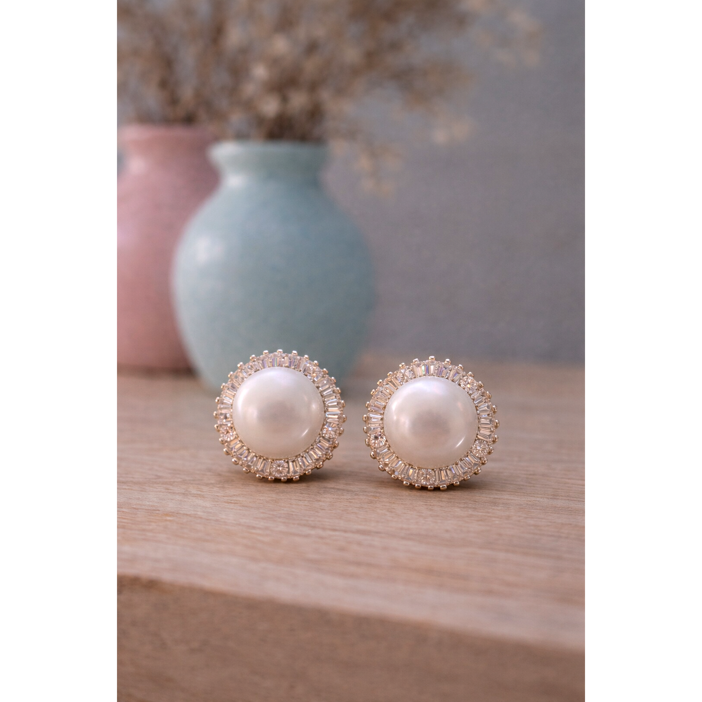 Silver tone pearl halo clip on stud earrings with baguette crystal surround placed on wooden surface