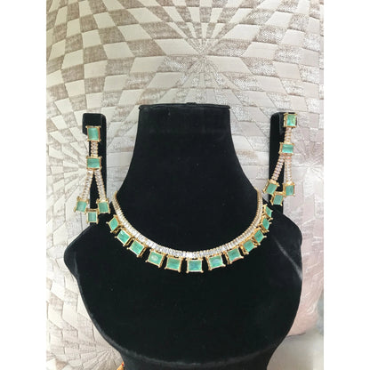 Necklace with green square stones on a black velvet stand against a textured wall.
