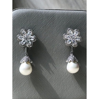 Pair of earrings with floral designs and pearls on a textured surface