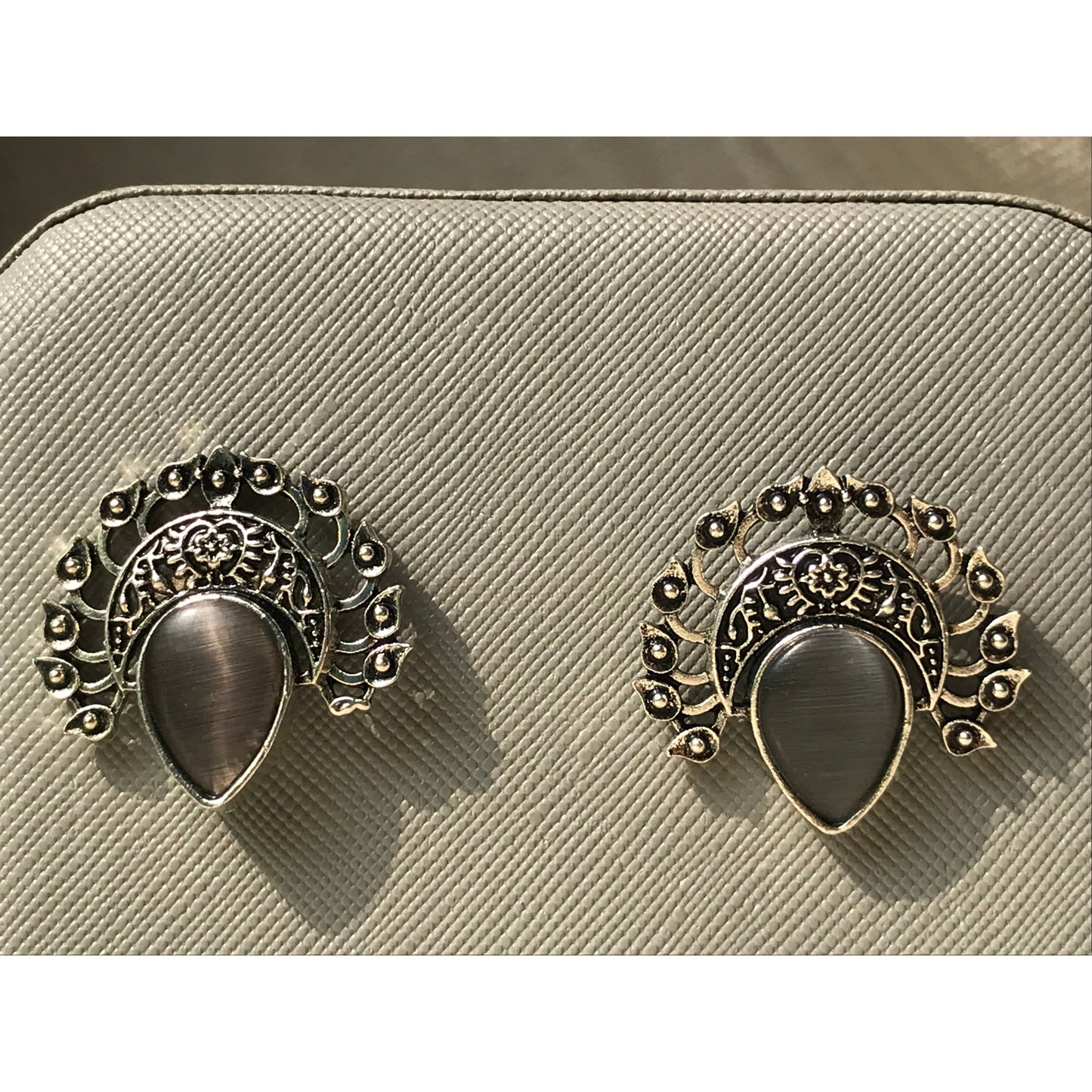 Pair of ornate earrings on a beige textured surface