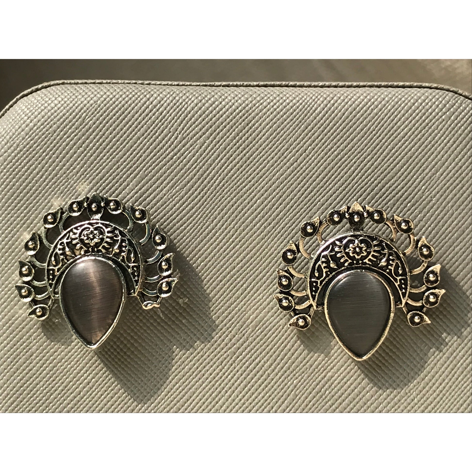 Pair of ornate earrings on a beige textured surface
