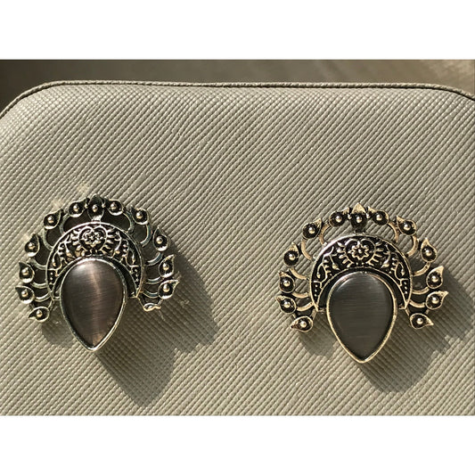 Pair of ornate earrings on a beige textured surface