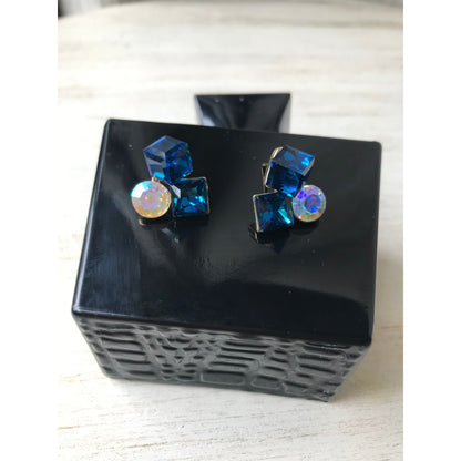 Blue gemstone earrings on a black stand with a white background