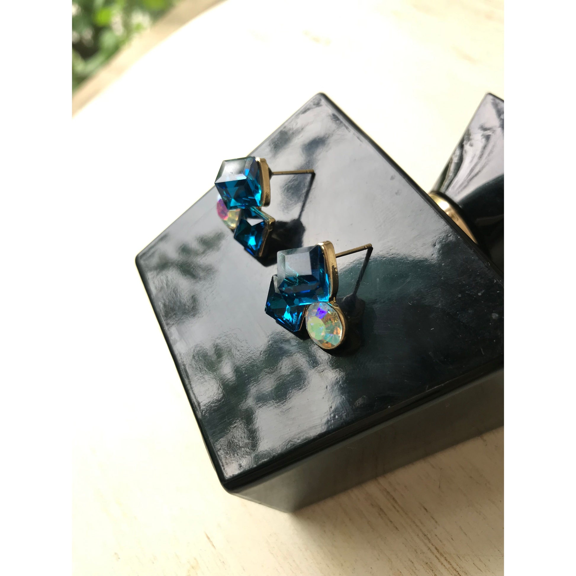 Pair of earrings with blue gemstones on a reflective surface