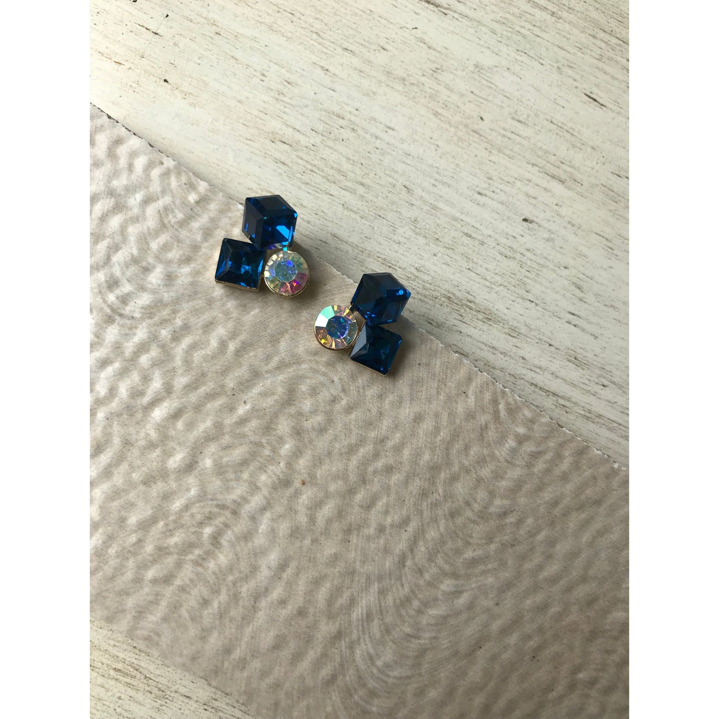 Blue crystal earrings on a textured surface