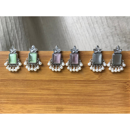 Set of three pairs of earrings with different colored gemstones on a wooden surface.