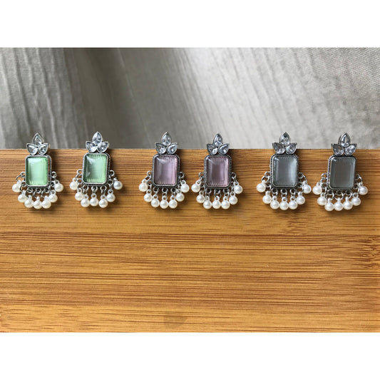 Set of three pairs of earrings with different colored gemstones on a wooden surface.