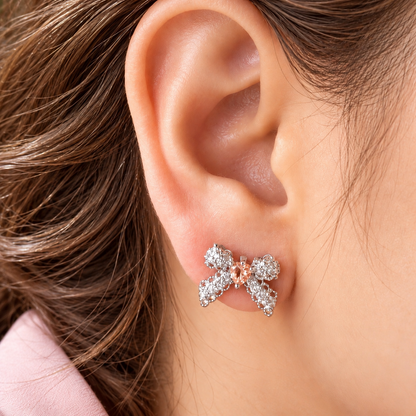 Close-up of a woman's ear wearing an Amorette Bow Stud with an  champagne centre stone and delicate clear zircon embellishments.