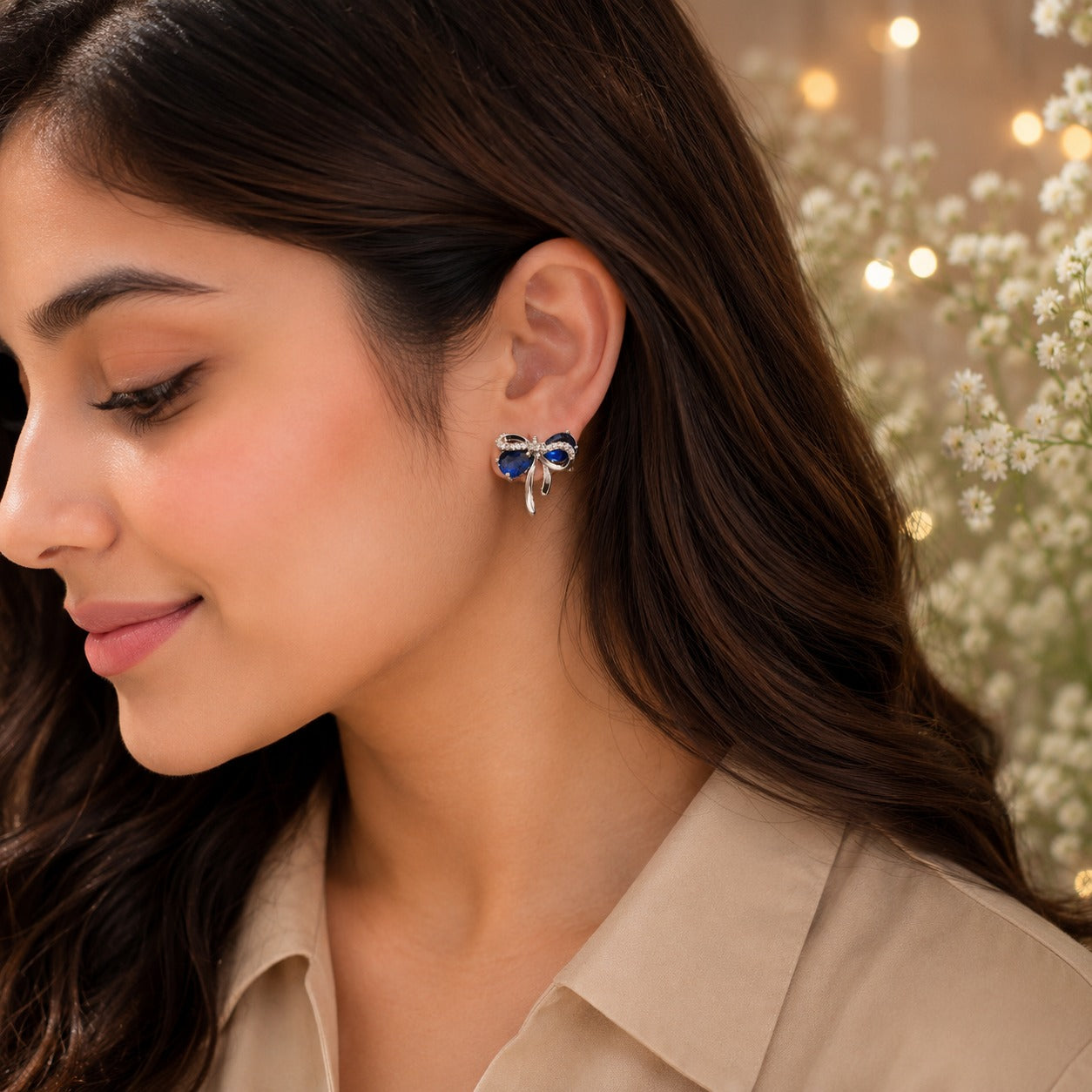 Sapphire blue bow stud earrings worn by model with beige satin shirt