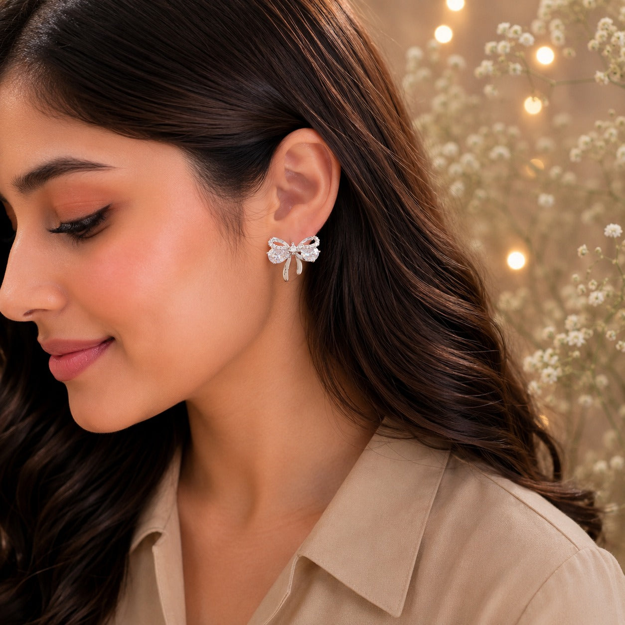 Crystal white bow stud earrings worn by model with beige satin shirt.