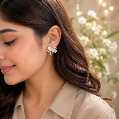 White opal bow stud earrings worn by model with beige satin shirt.