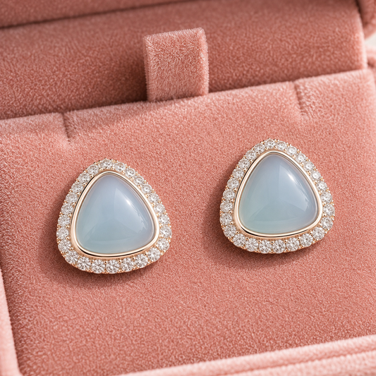 Pair of Glacier Cove Stud Earrings displayed in a blush pink jewellery box, featuring smooth ice-blue centres with clear zircon detailing.
