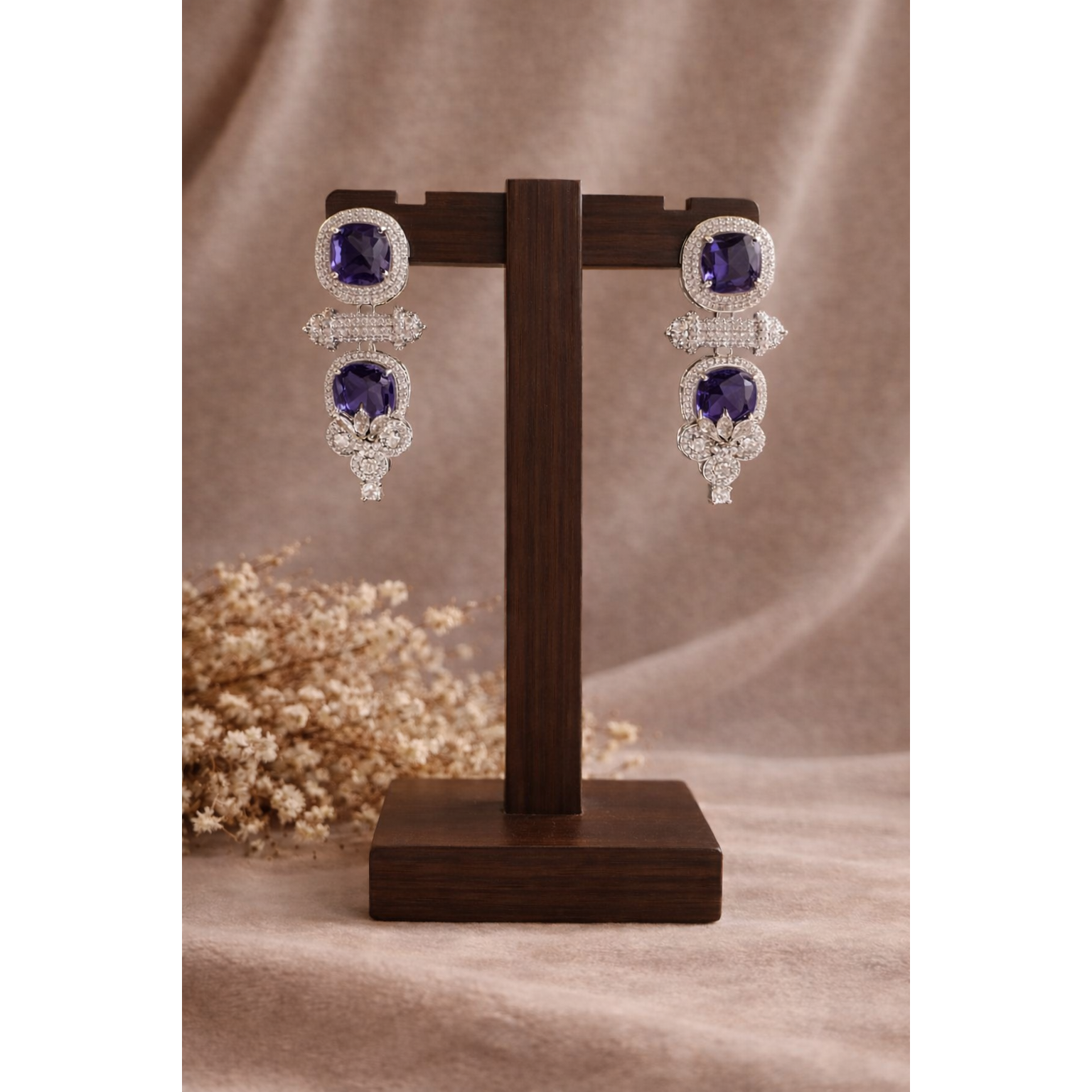 Blue cushion-cut statement drop earrings with pavé halo displayed on wooden stand