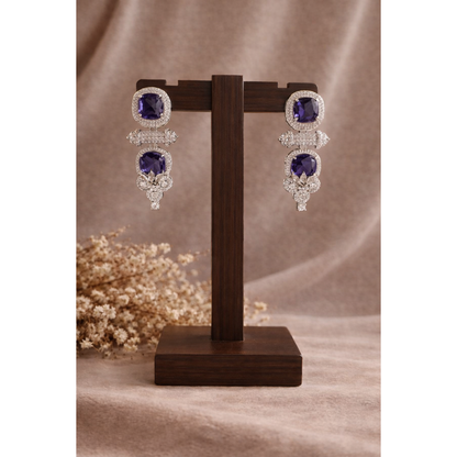 Blue cushion-cut statement drop earrings with pavé halo displayed on wooden stand
