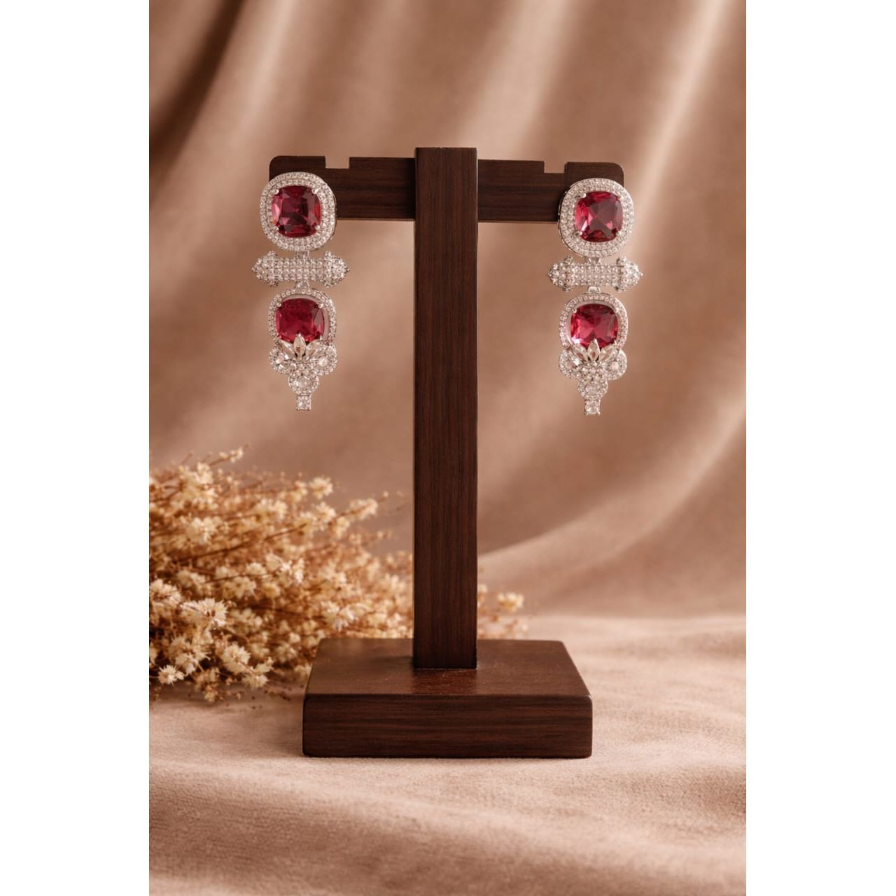 Pair of earrings on a wooden stand with a soft brown background