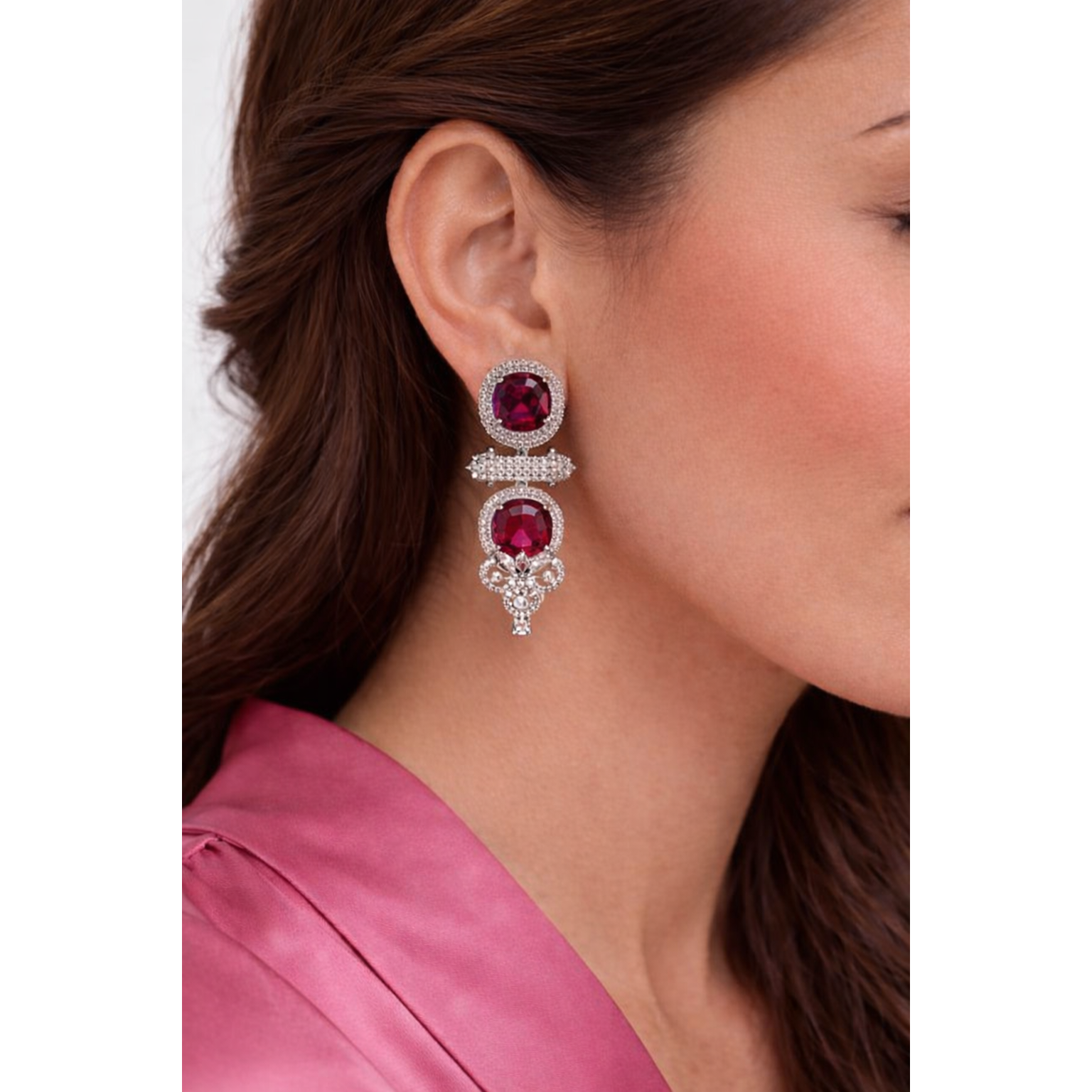 Close-up of a woman wearing a pair of Ruby Pink gemstone earrings with a pink satin top.