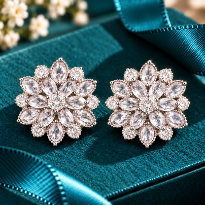 Vespera Bloom Earrings in clear featuring layered marquise-cut gemstones, clear zircon accents and polished silver-tone settings, displayed on a teal jewellery box
