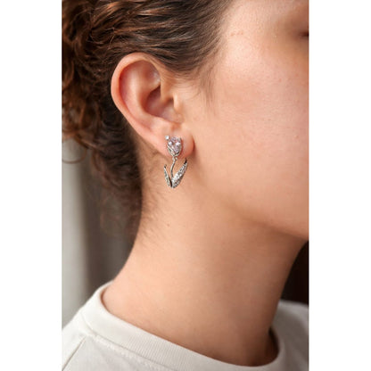 Close-up of a silver tulip-shaped drop earring with a  soft lavender crystal ,faceted gemstone and pavé leaf detail worn on a woman’s ear