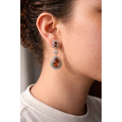 Close-up of a model wearing silver drop earrings with bronze crystal stones, featuring pavé detailing and a contemporary statement jewelry look.