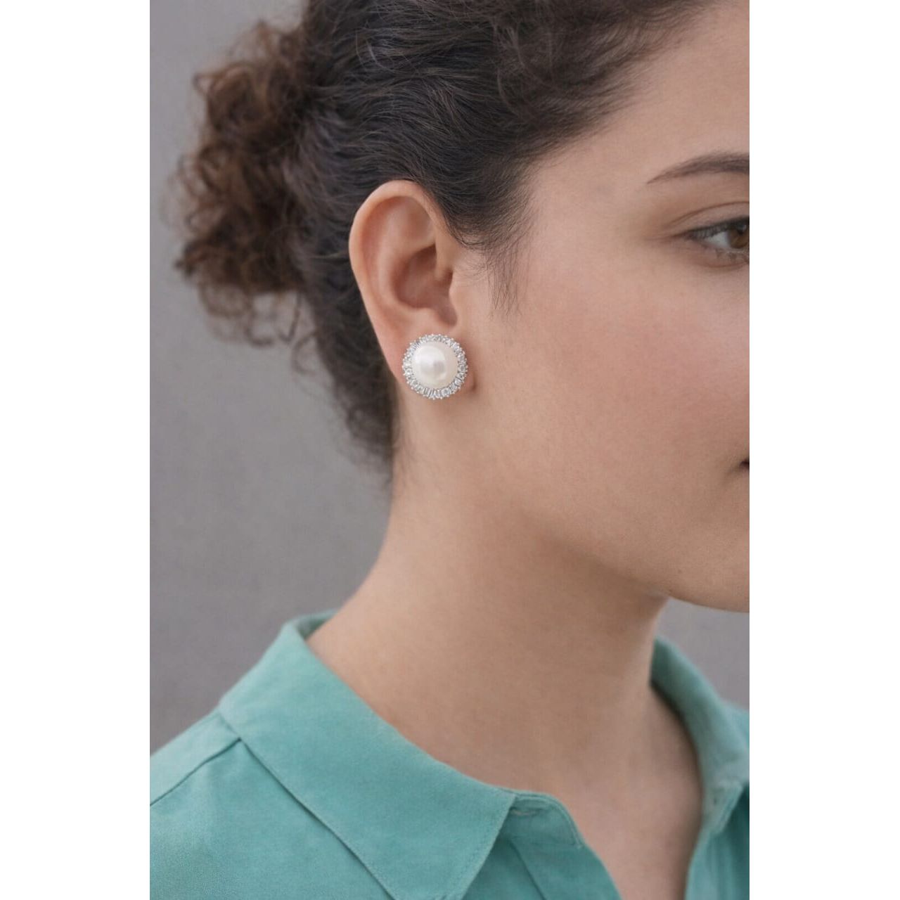 Woman wearing silver pearl halo clip on stud earrings with crystal border shown in side profile under soft lighting