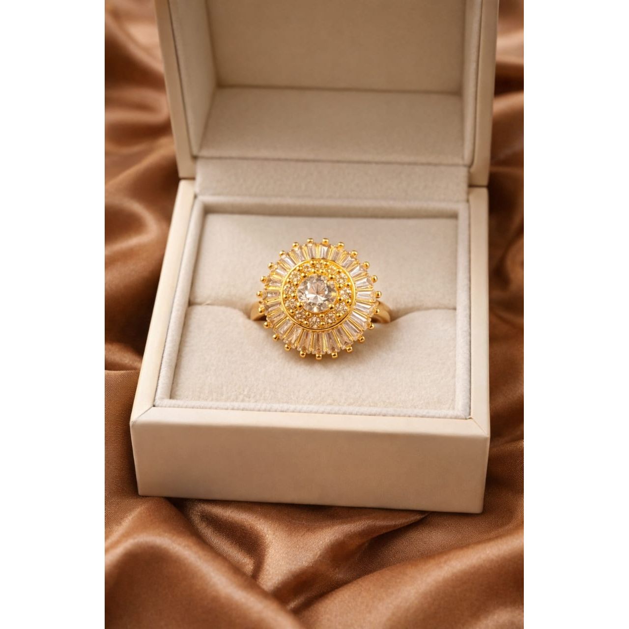 Gold halo statement ring with central round crystal and baguette halo displayed in luxury jewelry box on satin fabric
