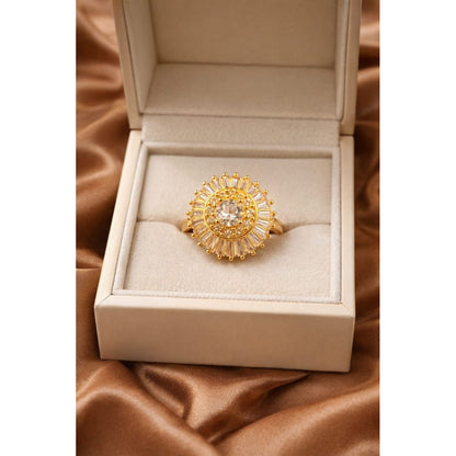 Gold halo statement ring with central round crystal and baguette halo displayed in luxury jewelry box on satin fabric
