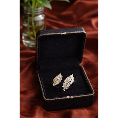 Silver leaf shaped statement ring with baguette cut stones displayed inside black jewelry box on rust satin background