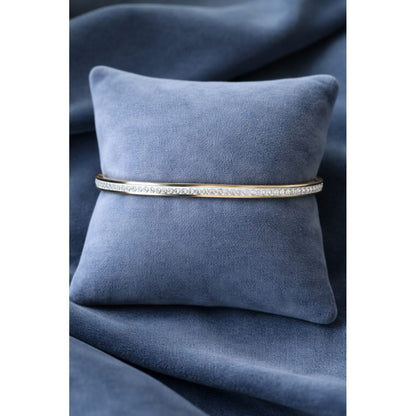 Gold crystal bracelet displayed on blue velvet cushion highlighting slim modern design and fine crystal detailing