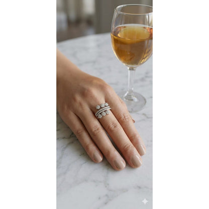 Silver floral cluster statement ring worn on hand with dual pavé bands on marble table setting