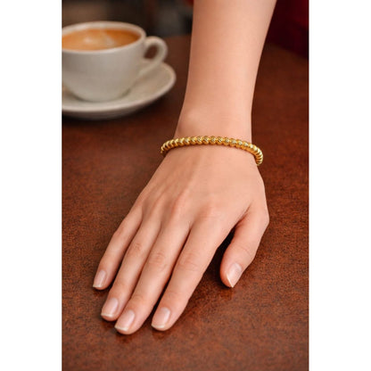 Gold textured bracelet with secure lock worn on feminine hand placed on café table, close-up luxury jewellery styling