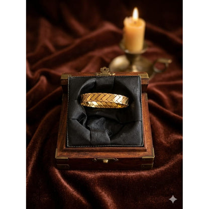 Gold woven texture bracelet with lock inside wooden jewelry box with black cushion and candlelight background