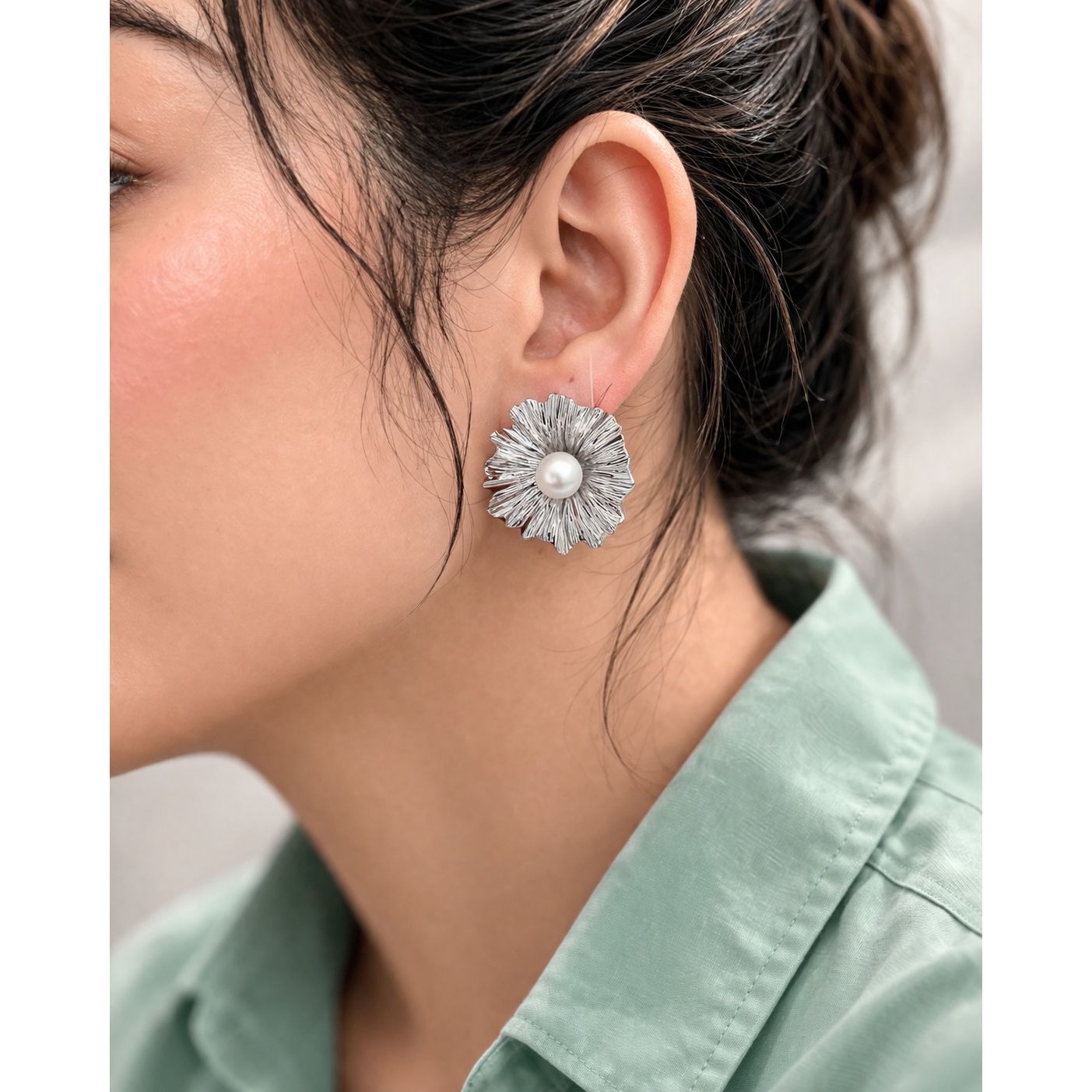 Side profile model wearing silver pearl floral stud earrings with textured petals 