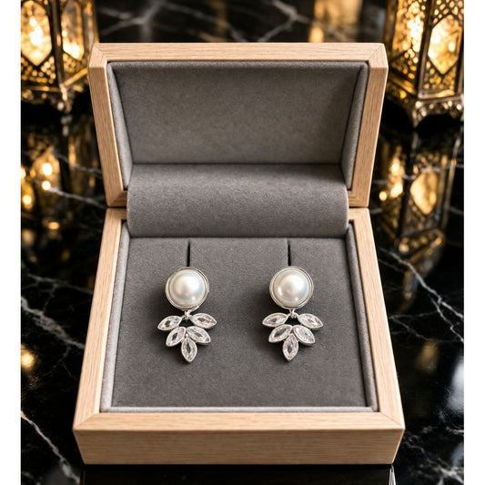Side profile model wearing silver pearl drop earrings with leaf motif design 