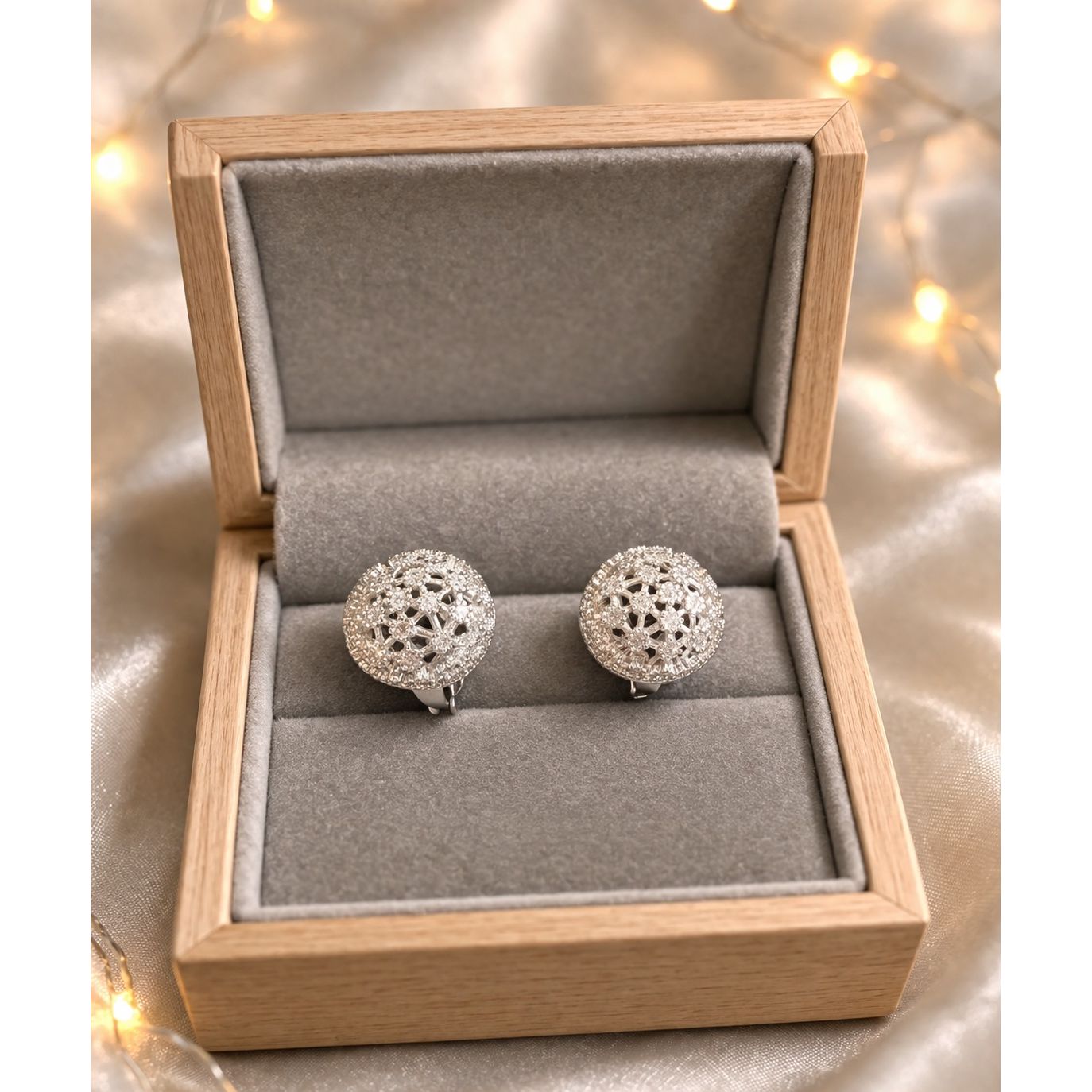 Silver crystal dome stud earrings placed in grey velvet jewelry box with warm ambient lighting