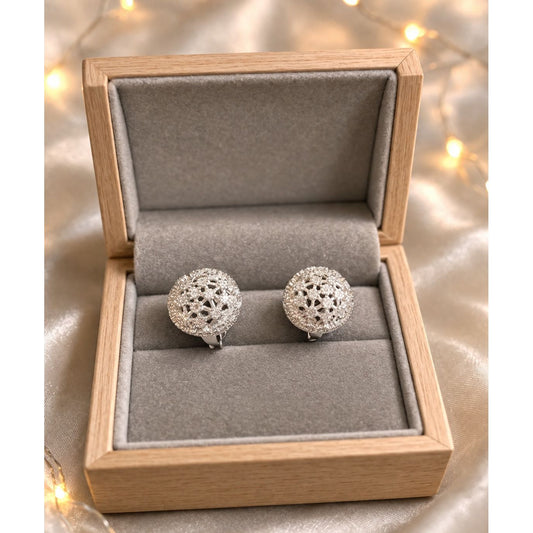 Silver crystal dome stud earrings placed in grey velvet jewelry box with warm ambient lighting