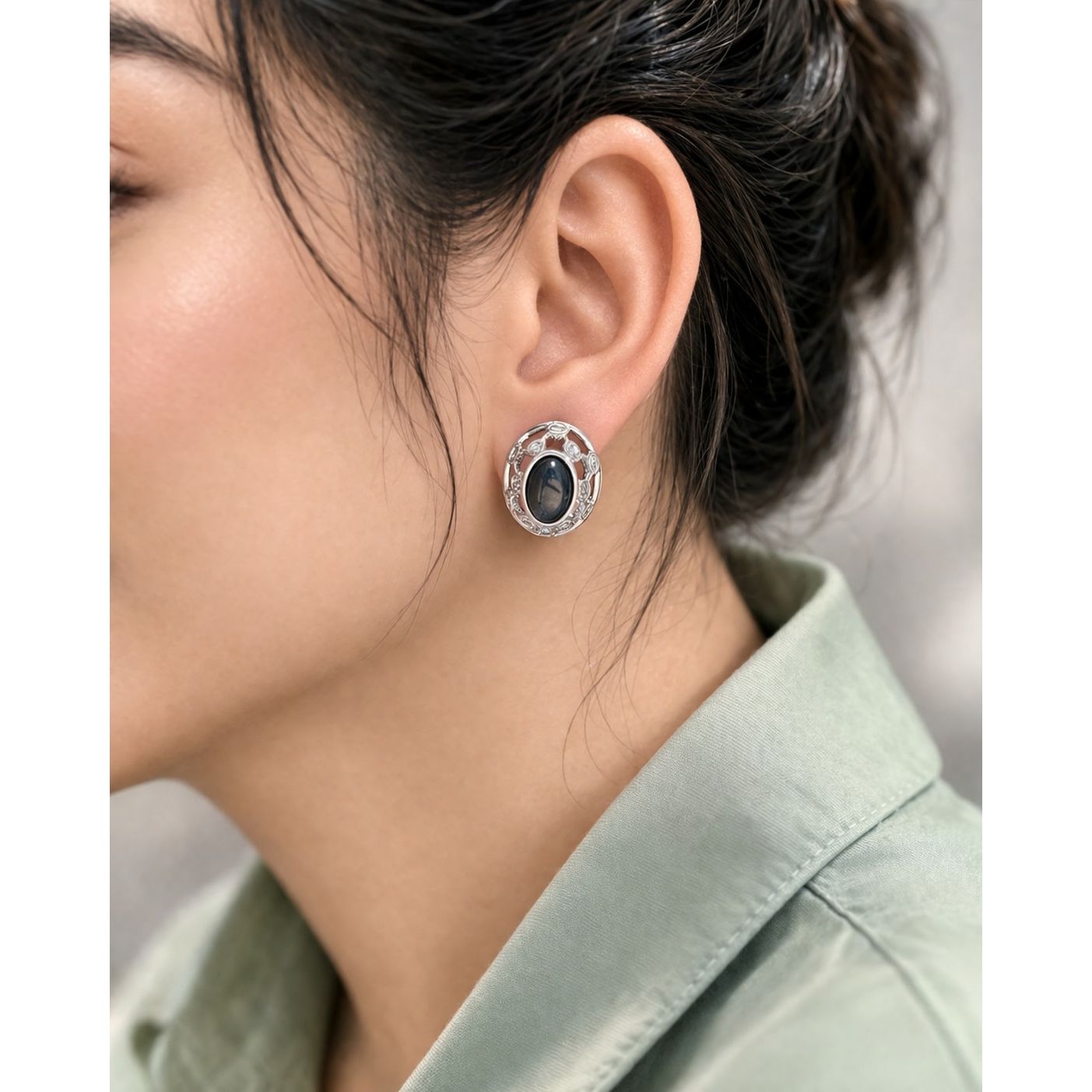 Silver oval black stone stud earrings worn on ear with soft natural lighting and minimal styling