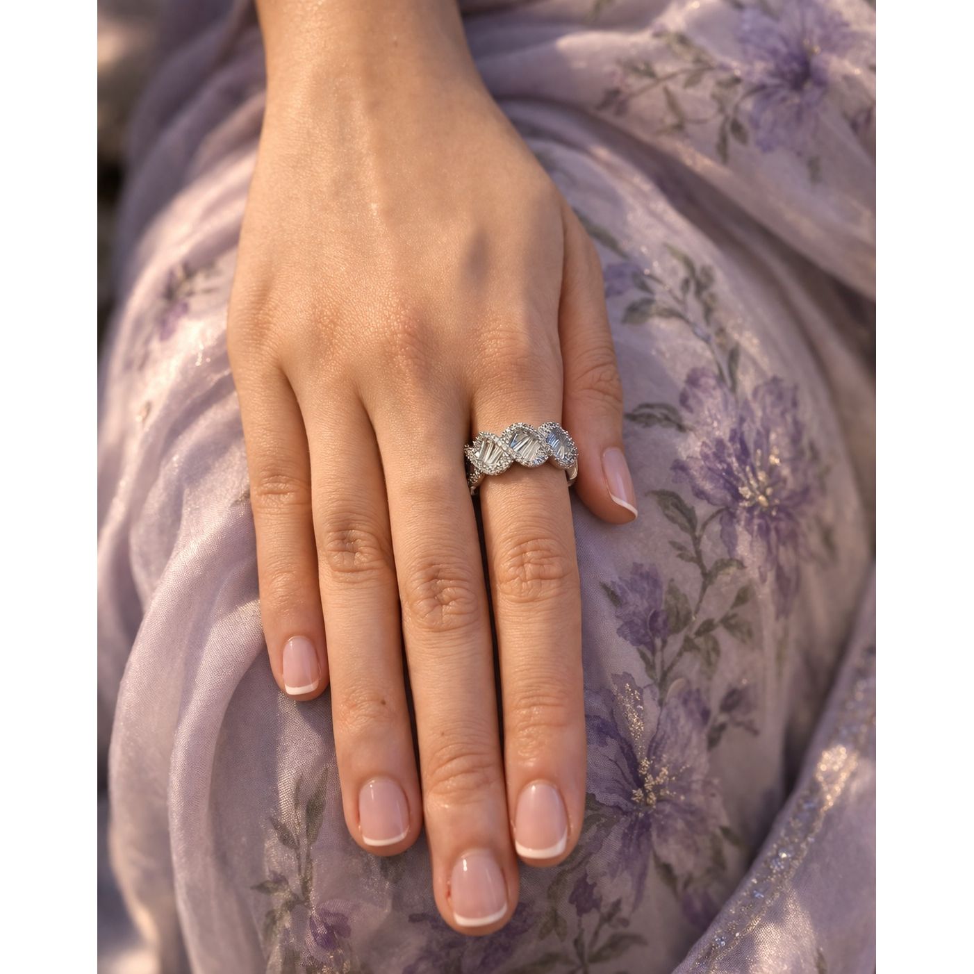 Silver textured open ring worn on hand with soft floral fabric background
