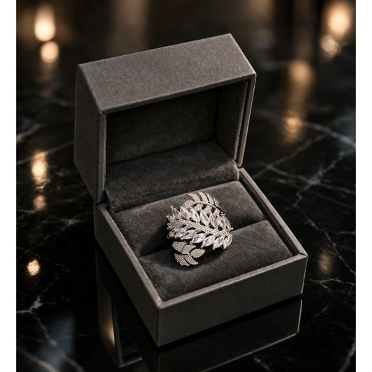 Silver leaf pattern marquise crystal ring displayed in premium dark jewelry box on marble surface