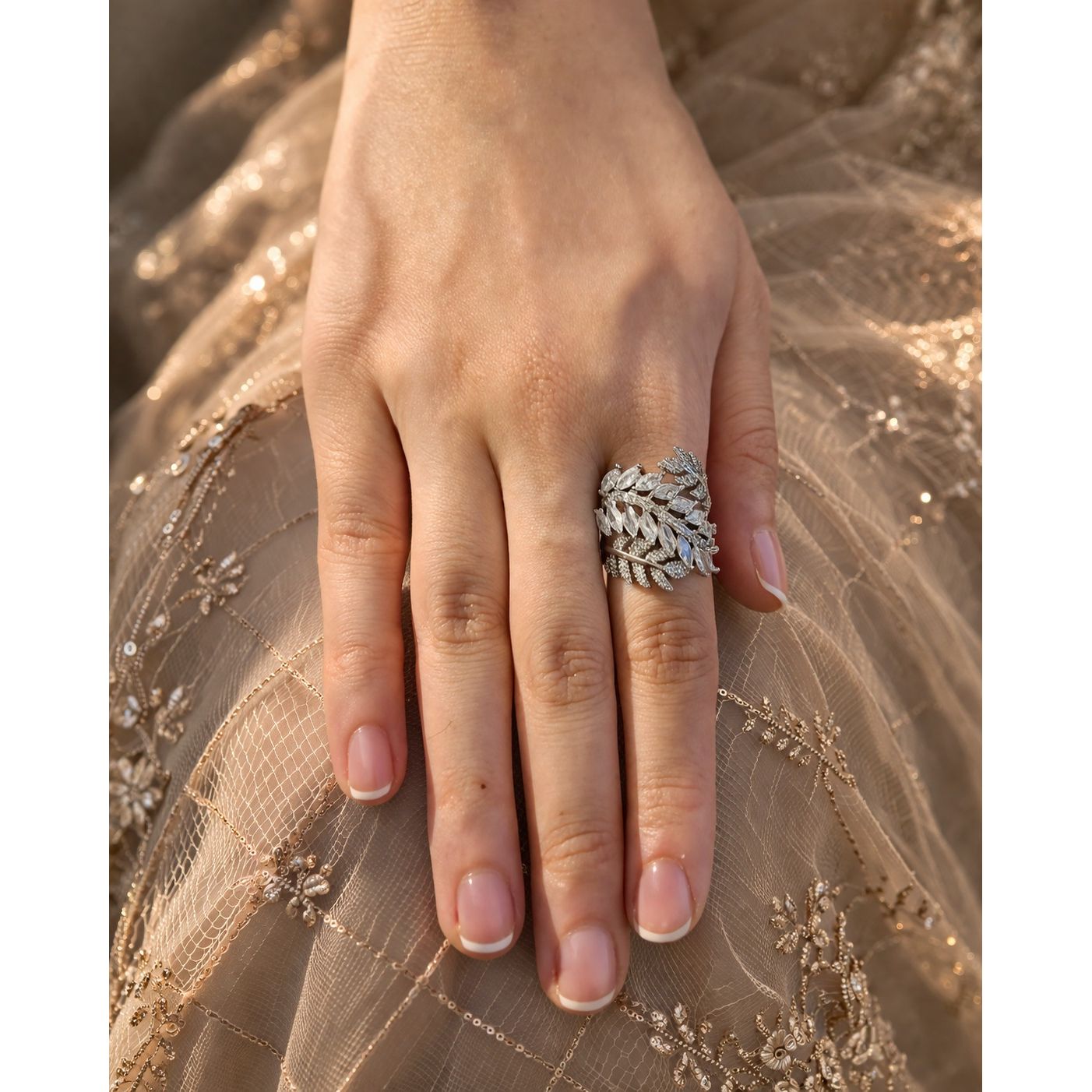 Silver leaf design statement ring with marquise crystals worn on hand with embroidered fabric background