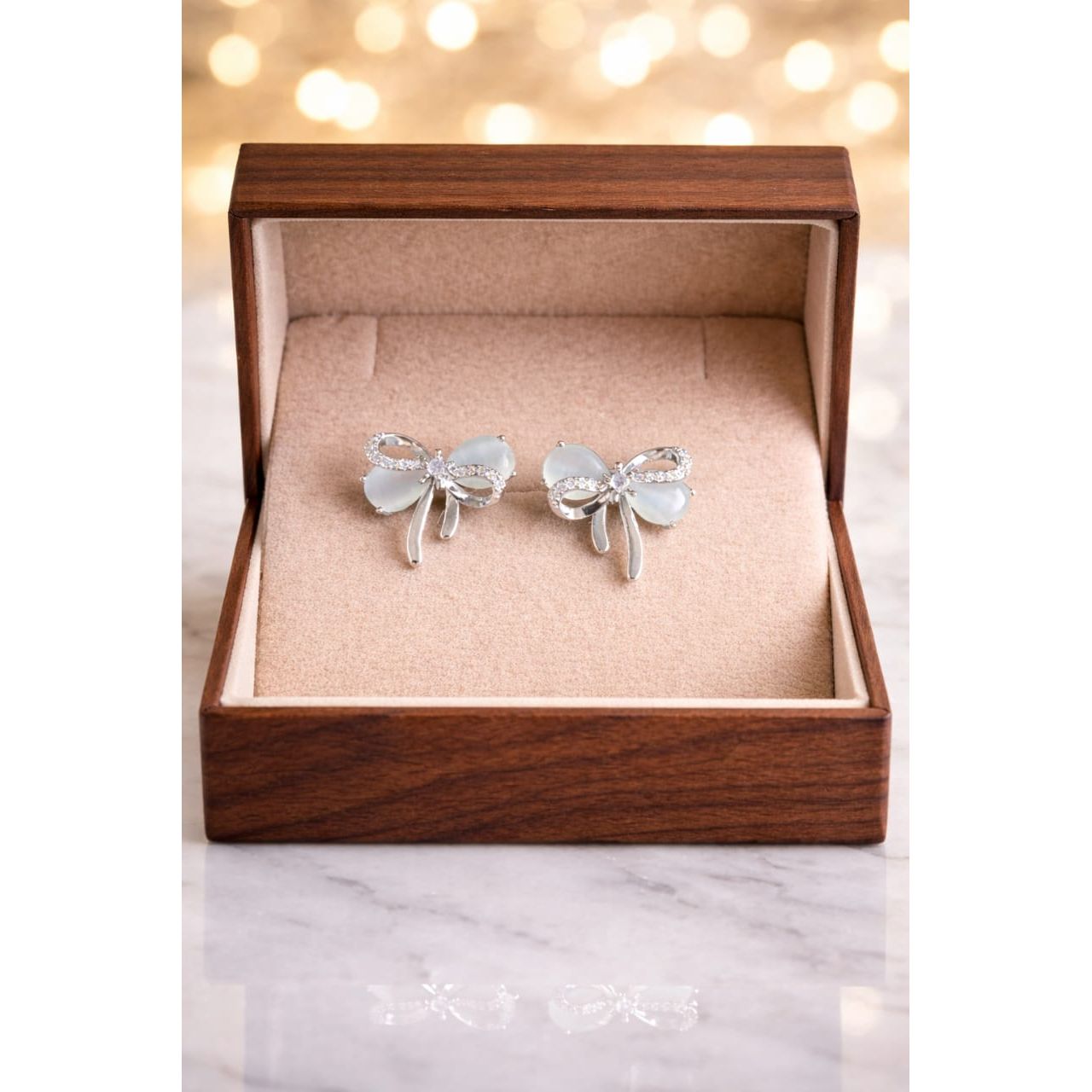 Silver bow knot stud earrings with crystal detailing placed in premium jewelry box