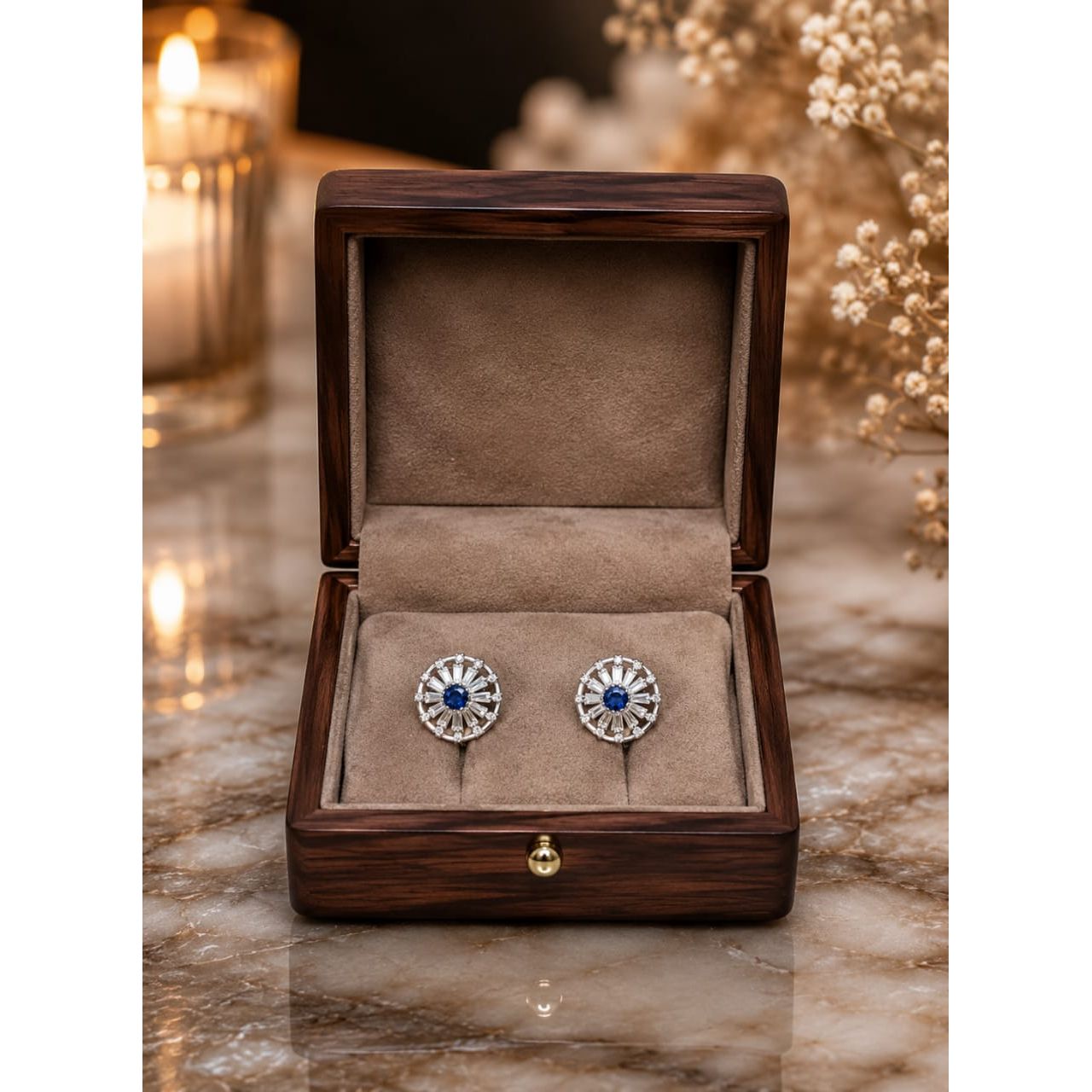 Silver and blue stud earrings in wooden jewelry box on marble surface