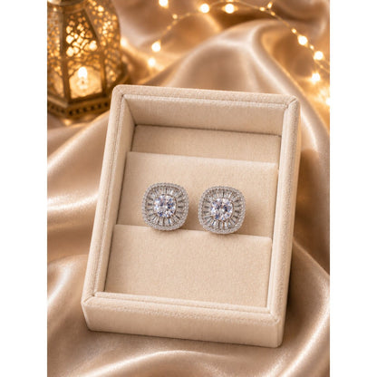 Silver halo stud earrings with crystal white center stones displayed in a luxury ivory jewelry box on champagne satin fabric with candlelit background.
