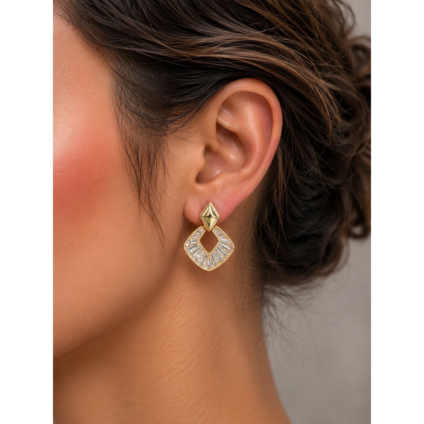 Gold geometric crystal earrings displayed in a premium charcoal velvet jewelry box with luxury studio lighting.