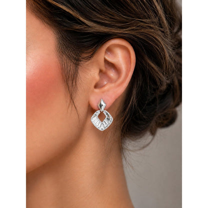 Woman wearing silver geometric crystal statement earrings with baguette-cut stones in a refined side-profile jewelry portrait.