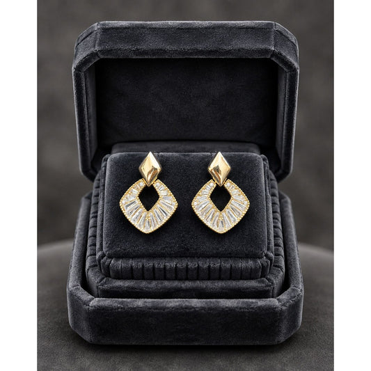 Gold geometric crystal earrings displayed in a premium charcoal velvet jewelry box with luxury studio lighting.