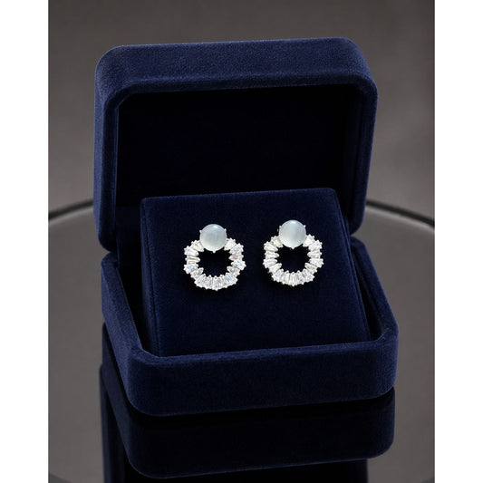 Moonstone halo crystal stud earrings displayed in a premium navy blue velvet jewelry box with sparkling baguette-cut stones and silver-tone finish.