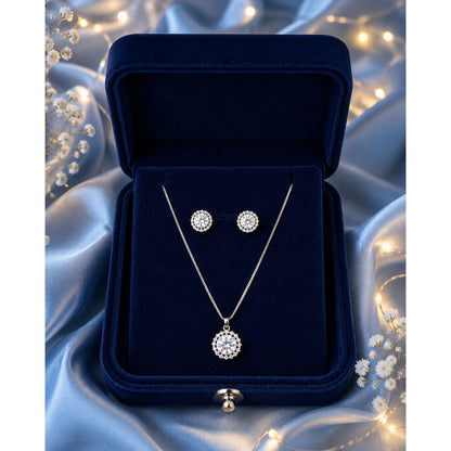 Silver halo crystal necklace and stud earring set displayed in a premium navy velvet jewelry box with soft fairy light background.